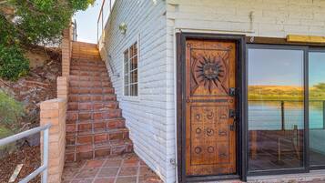 A wooden door with a sun design, a brick staircase, and a glass door leading to a view.