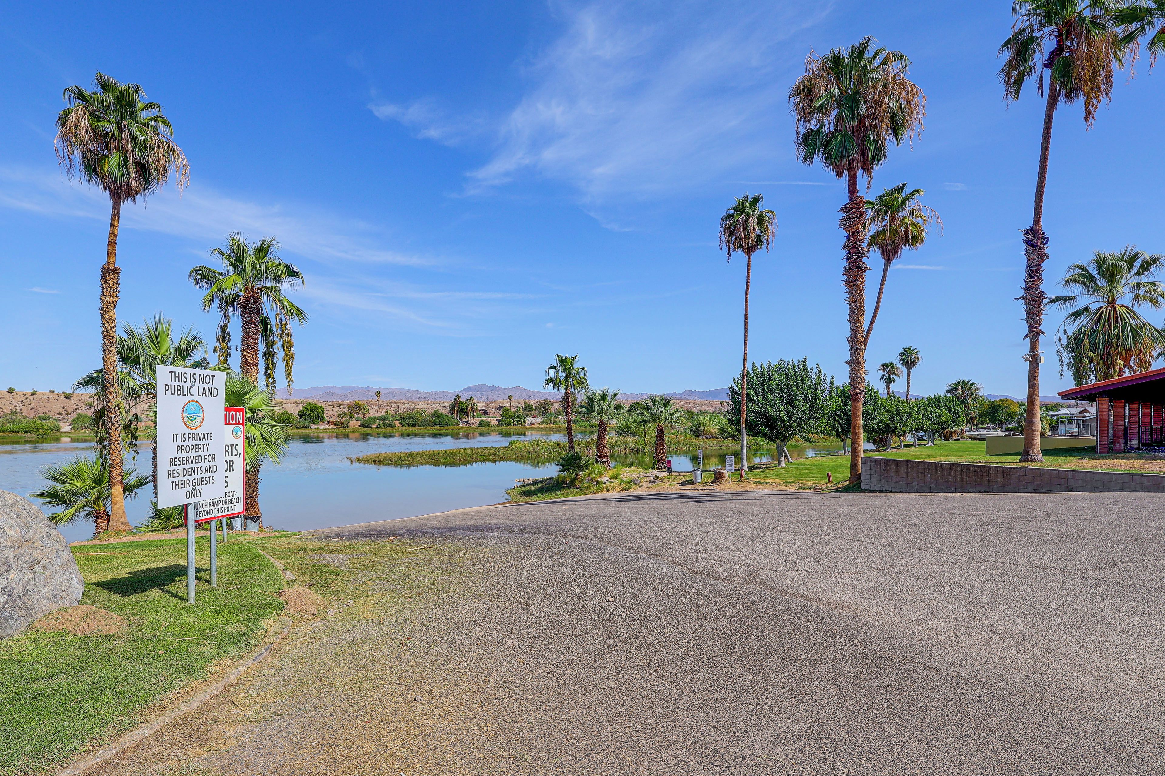 A gravel parking area with palm trees and a sign indicating private property.