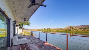 Un balcón con vistas a un río, un sofá blanco y un ventilador de techo.