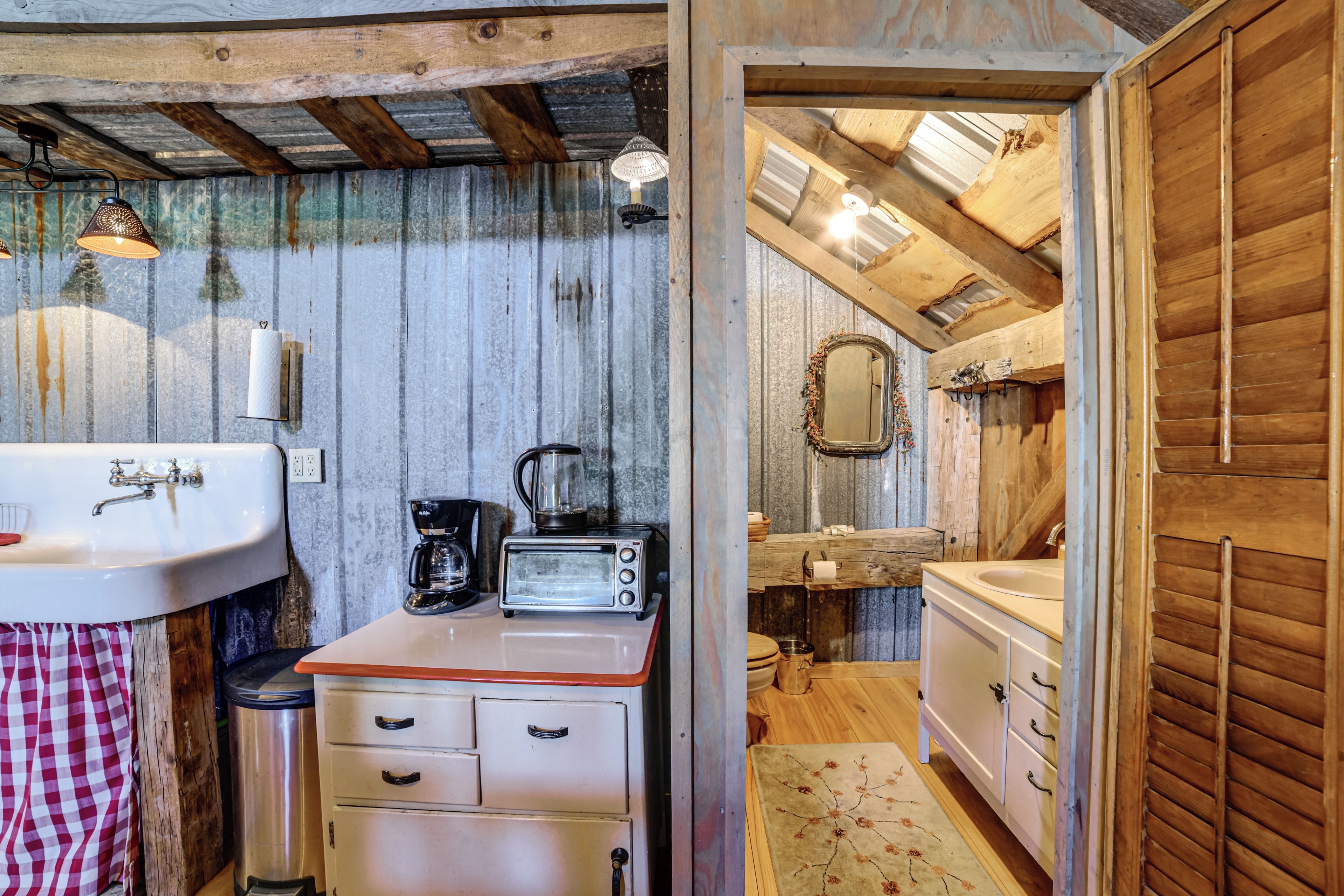 A rustic bathroom with a wooden ceiling, a sink, a toilet, and a mirror.