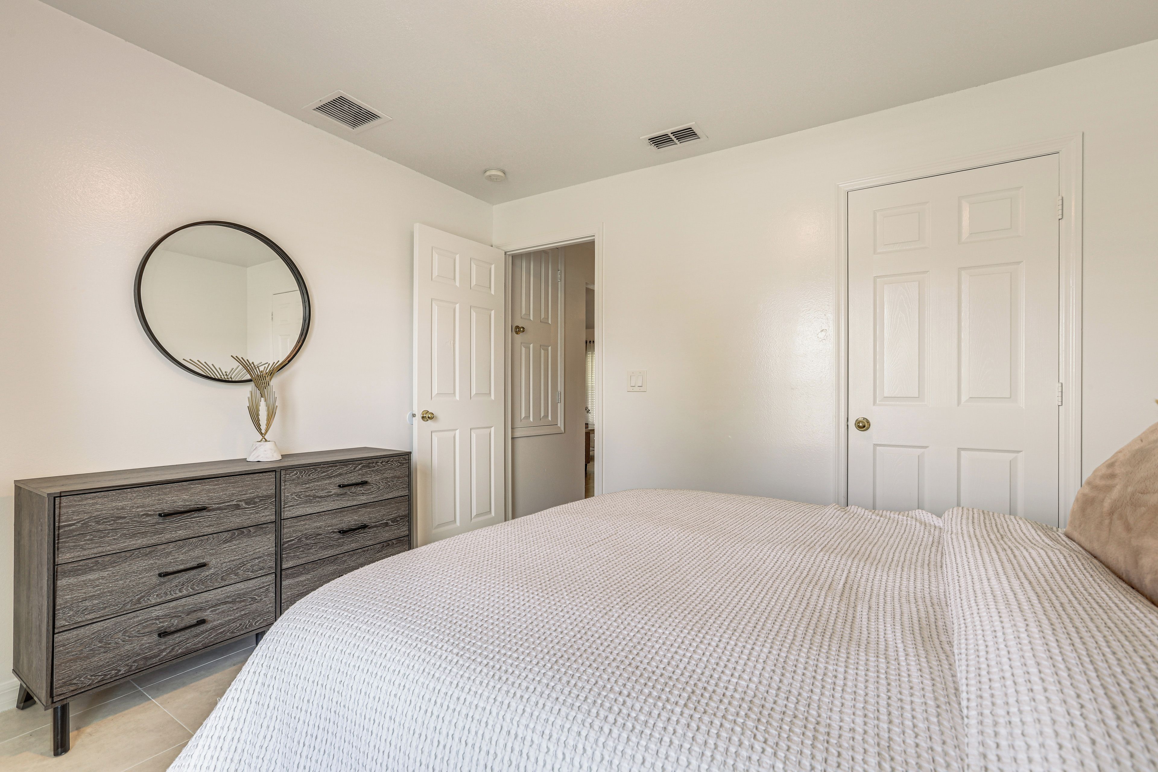 A bedroom with a bed, dresser, and a mirror.