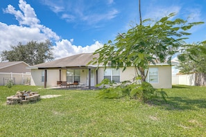 A single-story house with a covered patio, a lawn, and a tree in the foreground. - 13 Mi to Beach! Family Getaway in Port St Lucie (Port Saint Lucie)