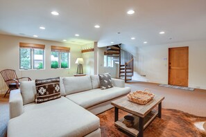 A modern living room with a sectional sofa, a wooden coffee table, and a spiral staircase. - 2 Mi to Sun Valley Resort! Upscale Mtn-view Home (Ketchum)