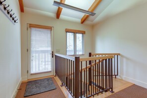 A staircase with wooden railings leading to an upper floor, a door with a window, and a small rug on the floor.