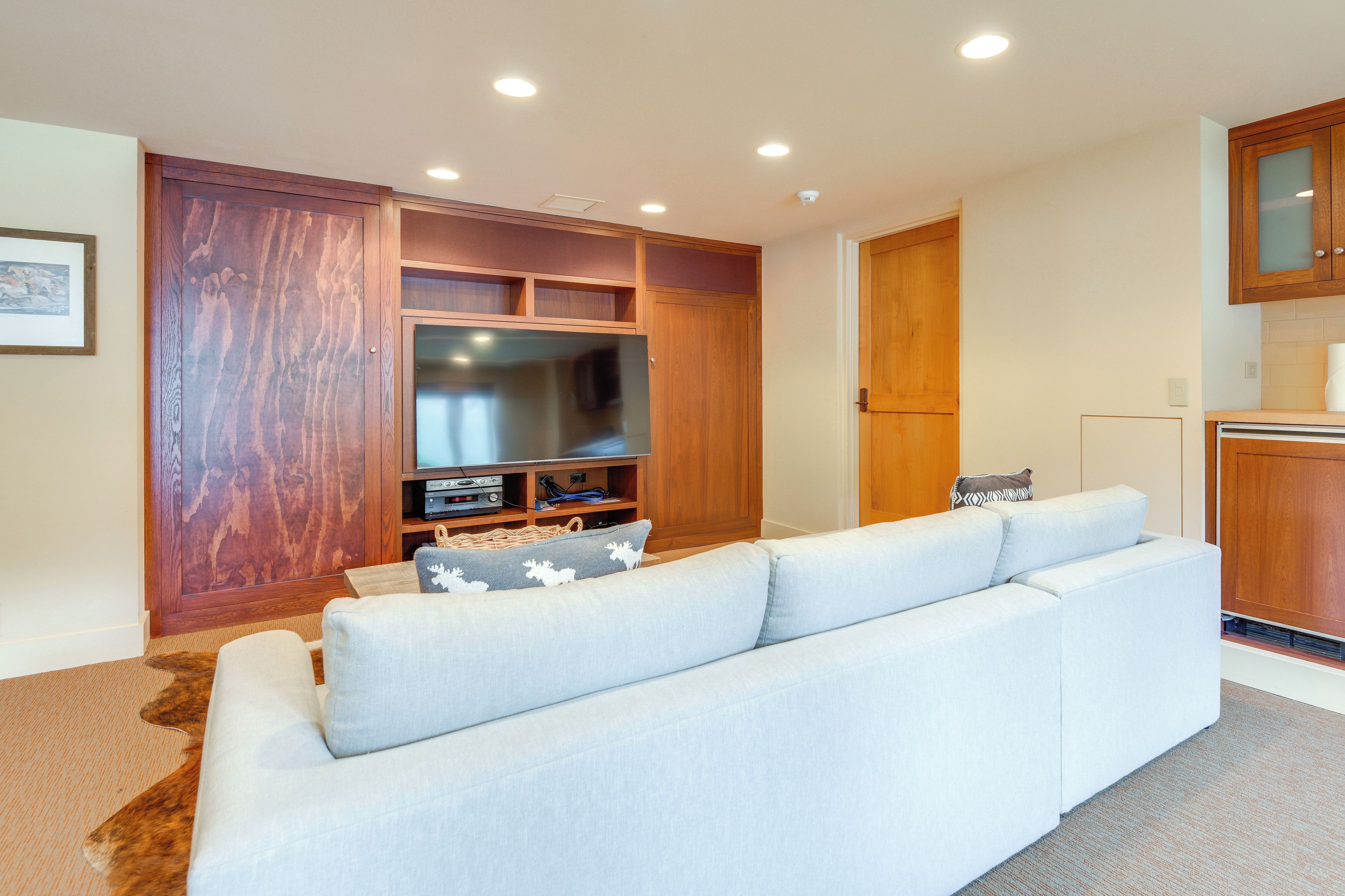A living room with a sofa, a television, wooden cabinets, and a fireplace.