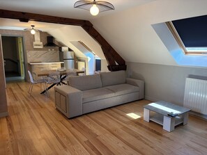 A loft-style living space with a dining area, kitchenette, and a large window.