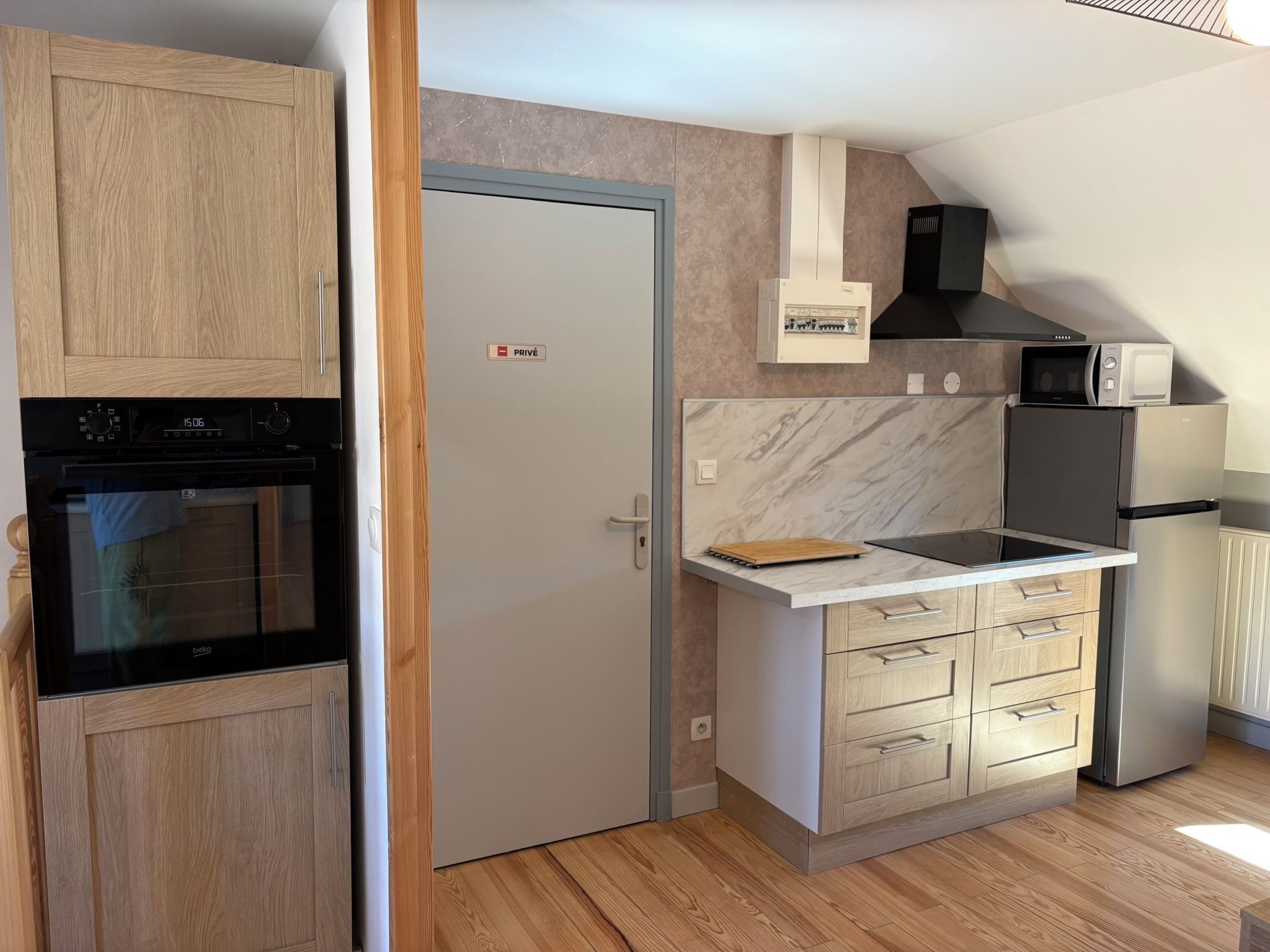 A compact kitchen with a built-in oven, a microwave, and a refrigerator.