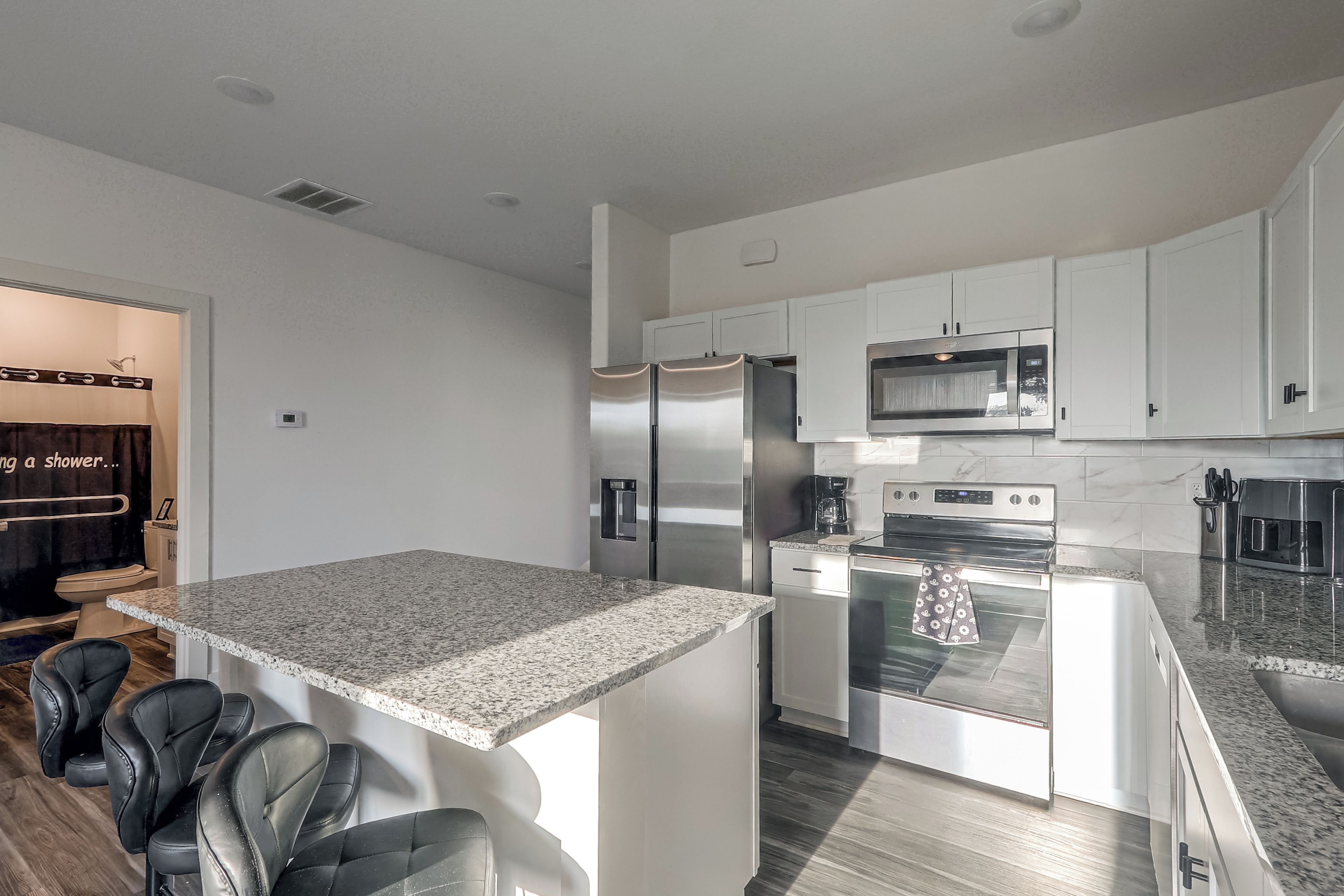 A modern kitchen with white cabinetry, stainless steel appliances, and a granite countertop.