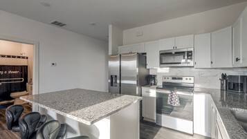 A modern kitchen with white cabinetry, stainless steel appliances, and a granite countertop.
