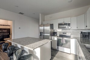 Una cocina moderna con armarios blancos, electrodomésticos de acero inoxidable y encimera de granito.