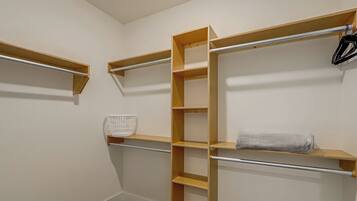 A walk-in closet with wooden shelves and a metal rod for hanging items.