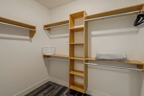 Un closet amplio con repisas de madera y una barra metálica para colgar ropa.