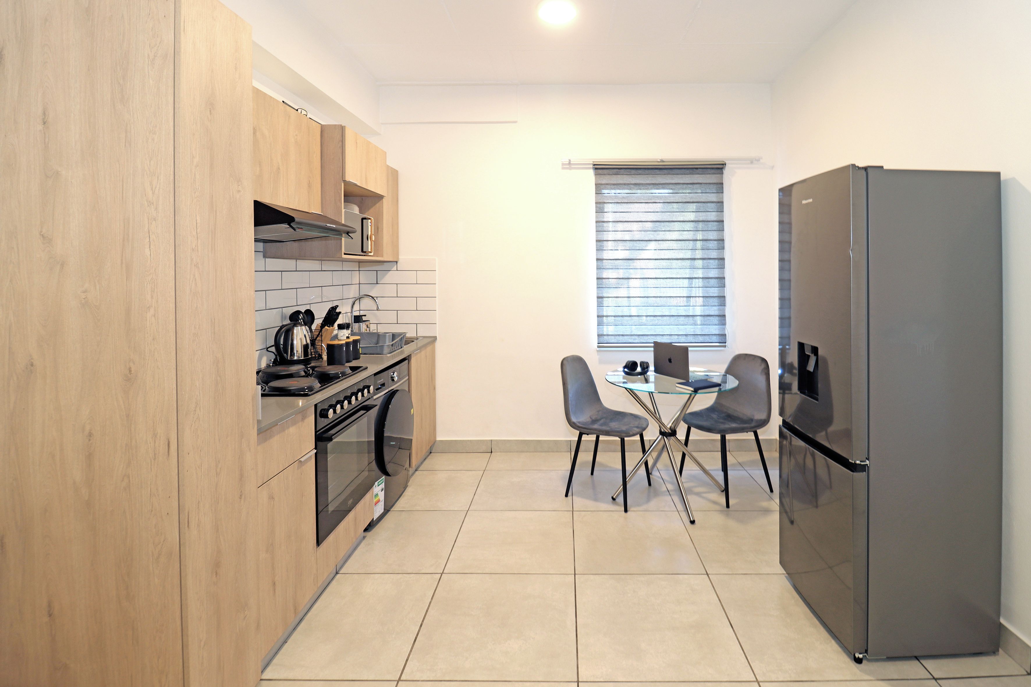 A compact kitchen with a built-in oven, a refrigerator, and a dining area with two chairs.