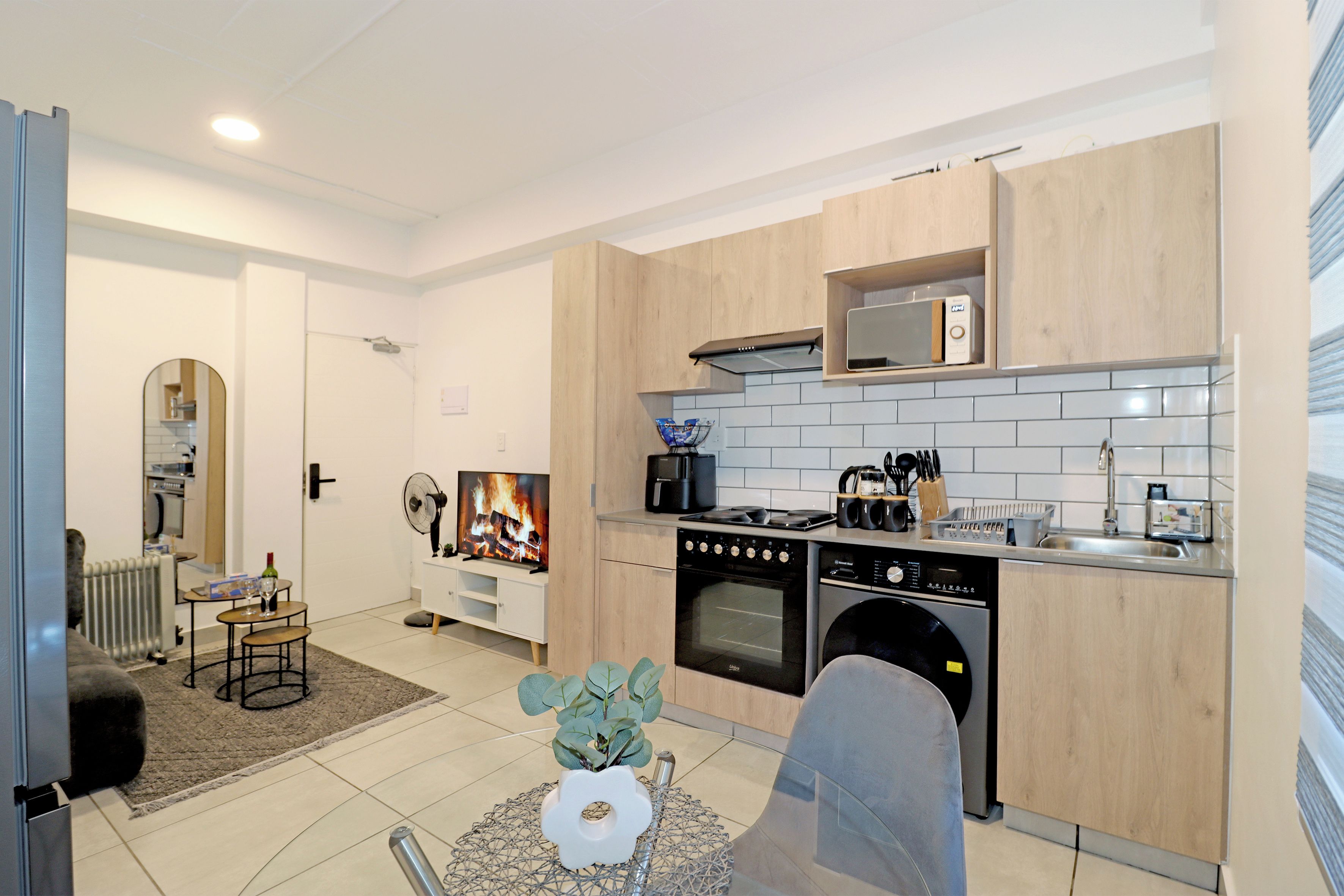 Une cuisine moderne avec des meubles en bois, un four encastré, un lave-vaisselle et un four à micro-ondes.