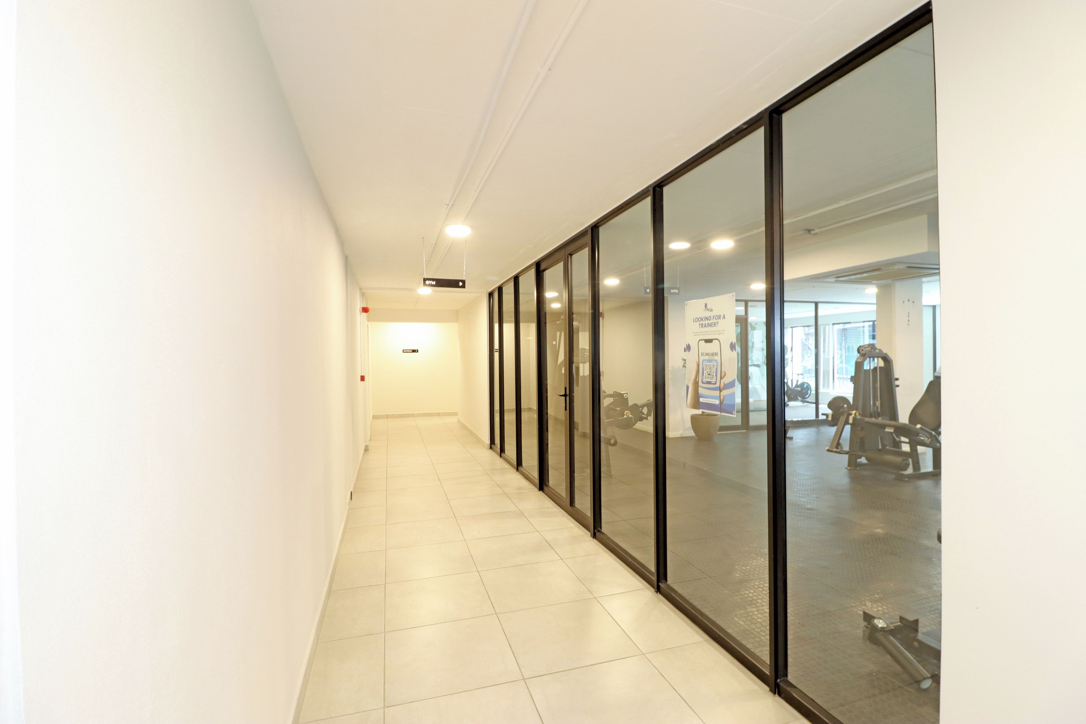 A corridor with glass doors leading to a gym area.