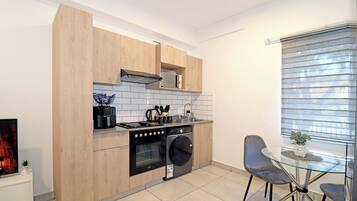 A modern kitchen with wooden cabinets, a built-in oven, a microwave, and a glass dining table with chairs.
