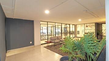 A modern interior with a seating area, large windows, and indoor plants.