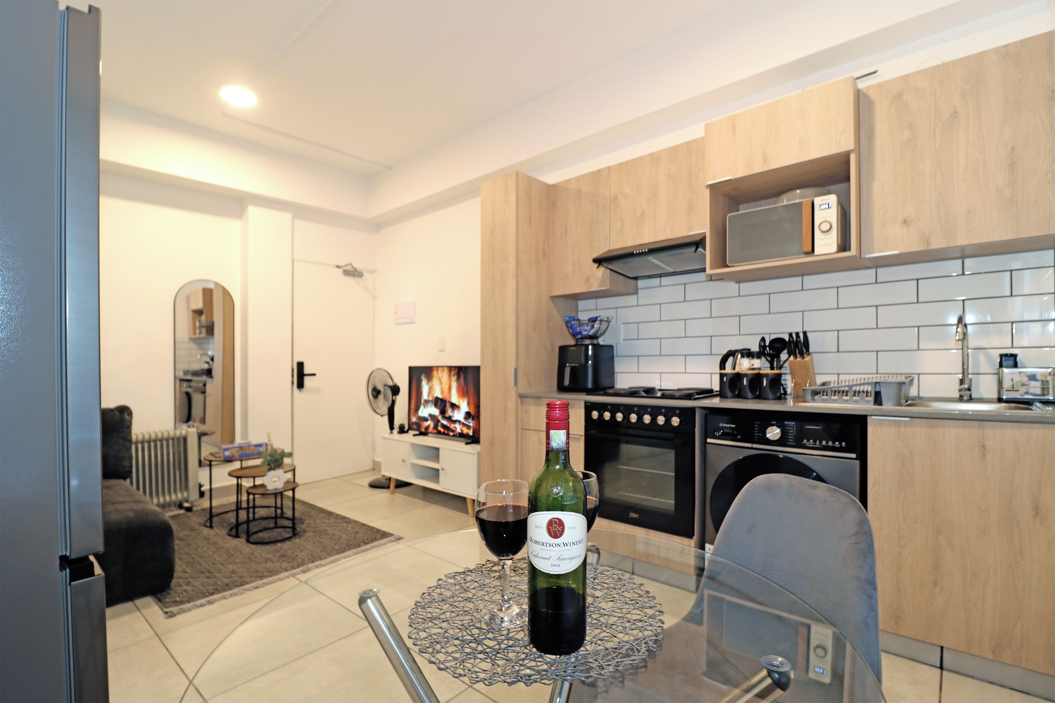 Une cuisine moderne avec un coin repas, une cheminée et une bouteille de vin posée sur une table.