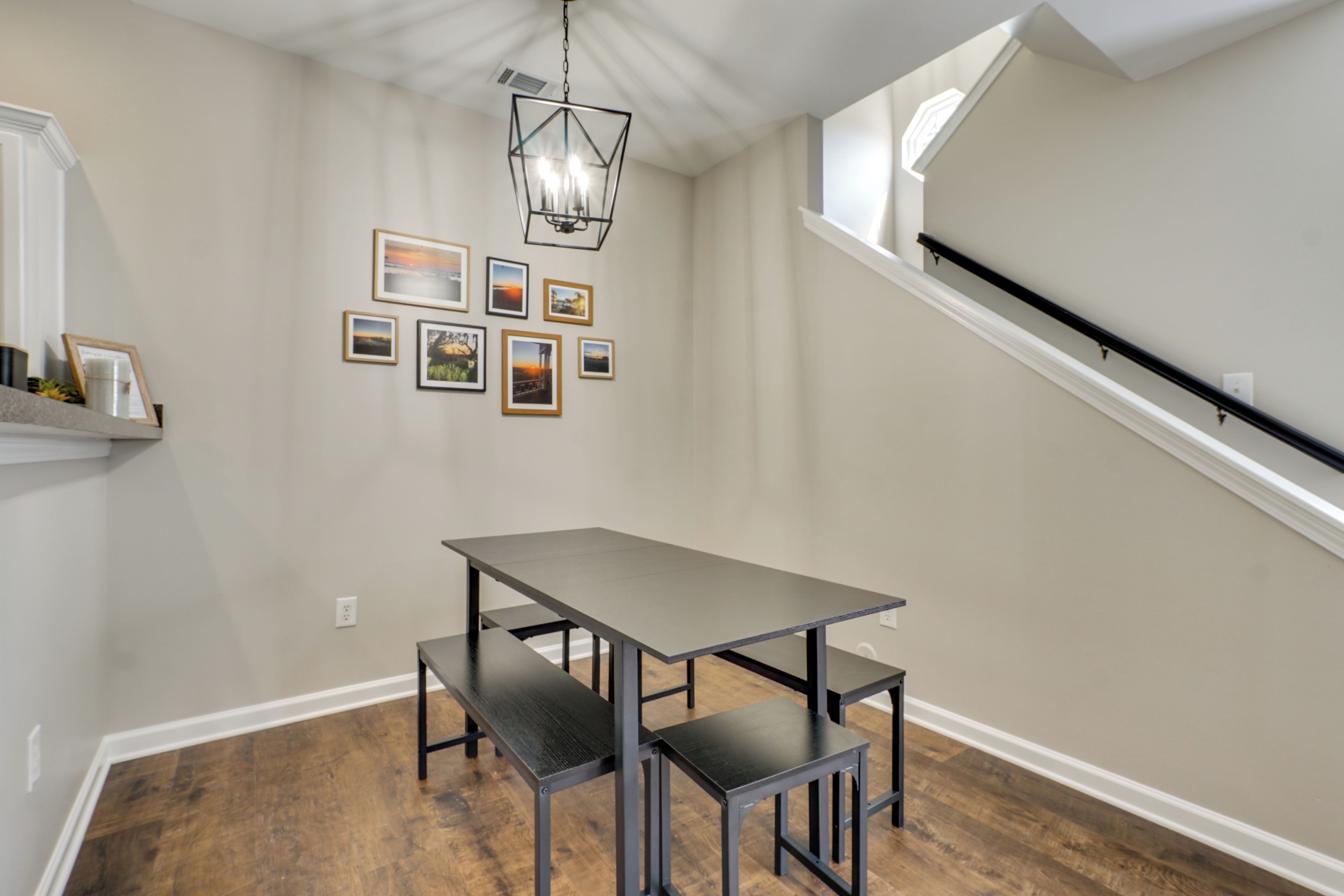 A dining area with a table and benches, a chandelier, and framed pictures on the wall.