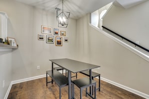 A dining area with a table and benches, a chandelier, and framed pictures on the wall.