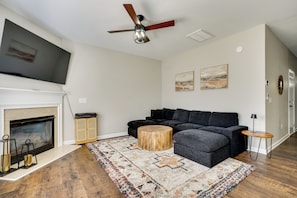 A living room with a fireplace, a sectional sofa, a coffee table, and a ceiling fan.