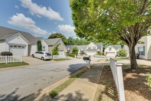 A residential street with houses, a white car parked on the street, and a mailbox.