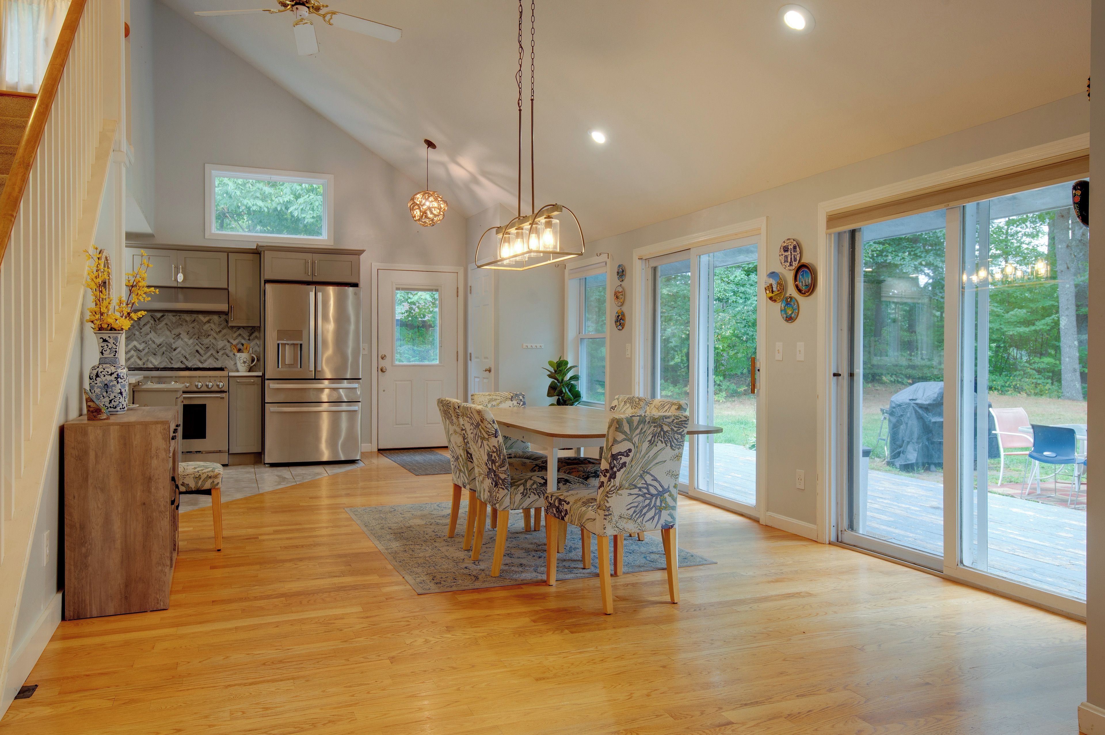 A spacious kitchen with modern appliances, a dining area with floral chairs, and large sliding glass doors leading to a patio.