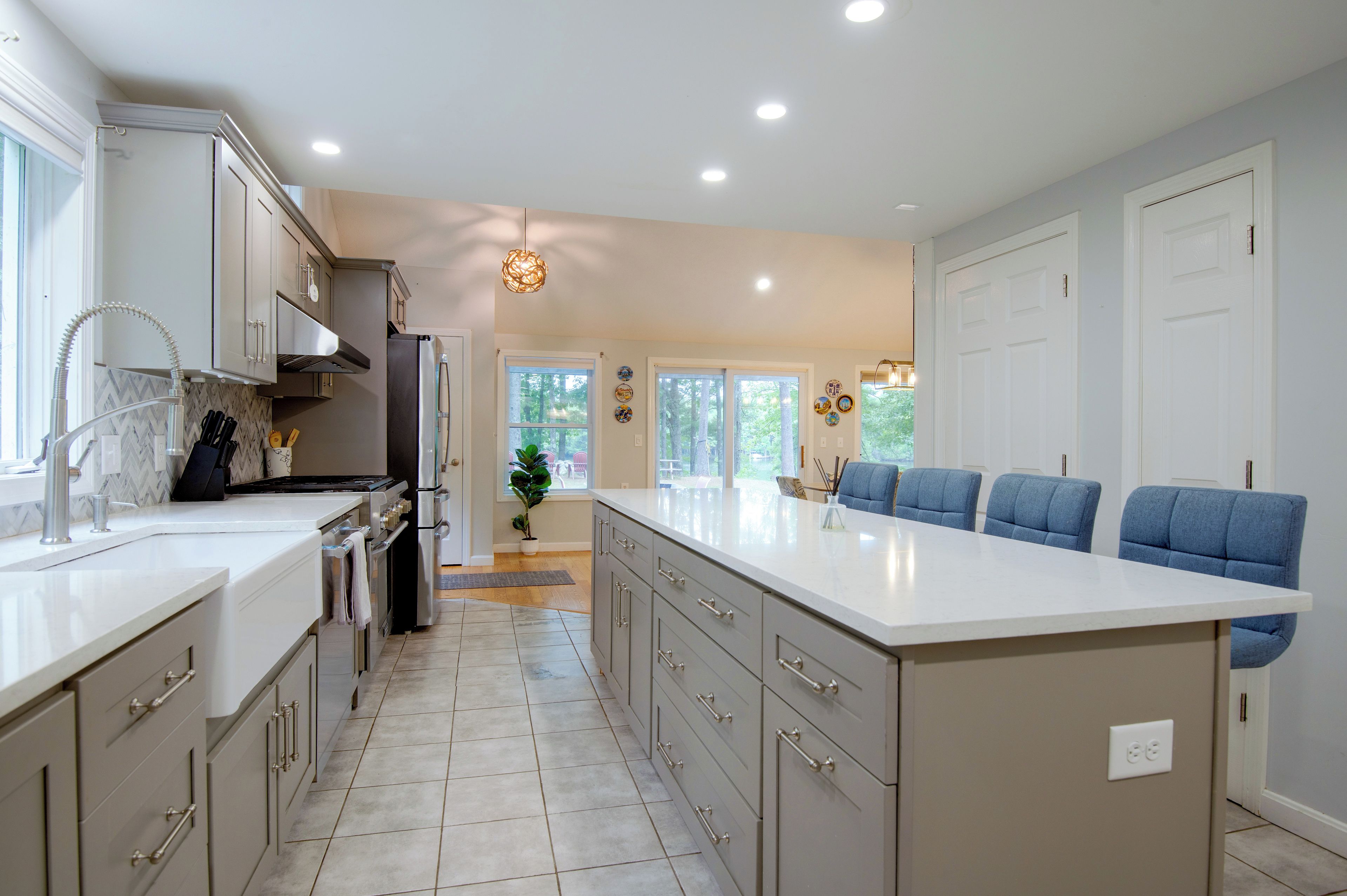 A modern kitchen with a large island, stainless steel appliances, and a view to the outdoors.