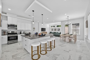 Cozinha moderna com ilha central, banquetas e área de jantar com mesa e cadeiras.