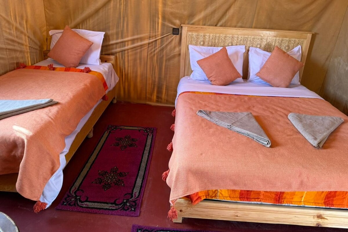 Two single beds with wooden frames and matching headboards, each with a white pillow and a peach-colored blanket.