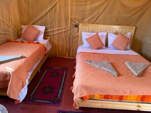 Two single beds with wooden frames and matching headboards, each with a white pillow and a peach-colored blanket. - luxury camp sable dor (Merzouga)