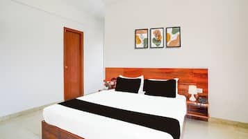 Een hotelkamer met een bed, een nachtkastje, een lamp en kunst aan de muur.