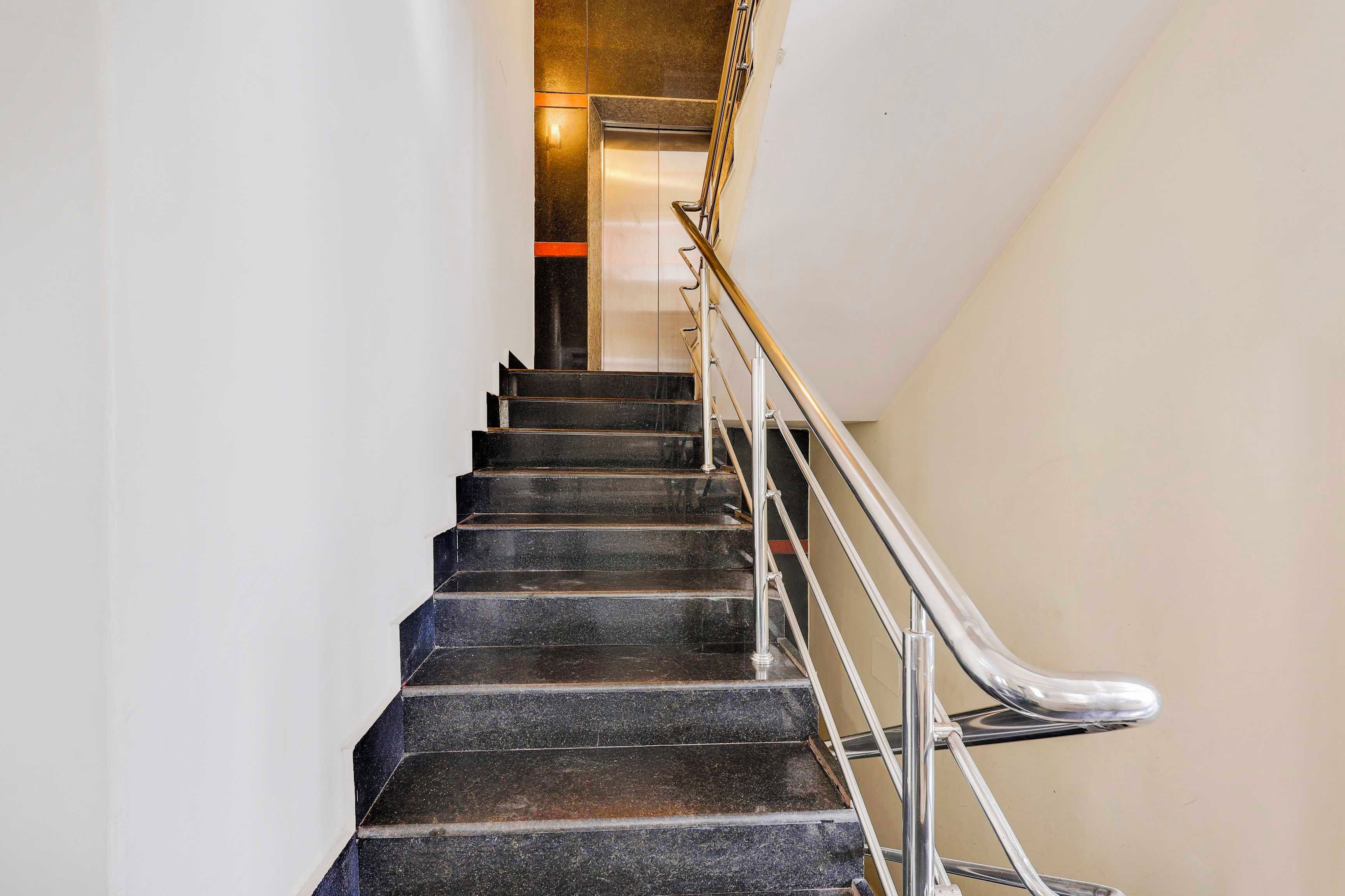 Una escalera con escalones negros y barandilla de metal.