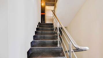 Una escalera con escalones negros y barandilla de metal.