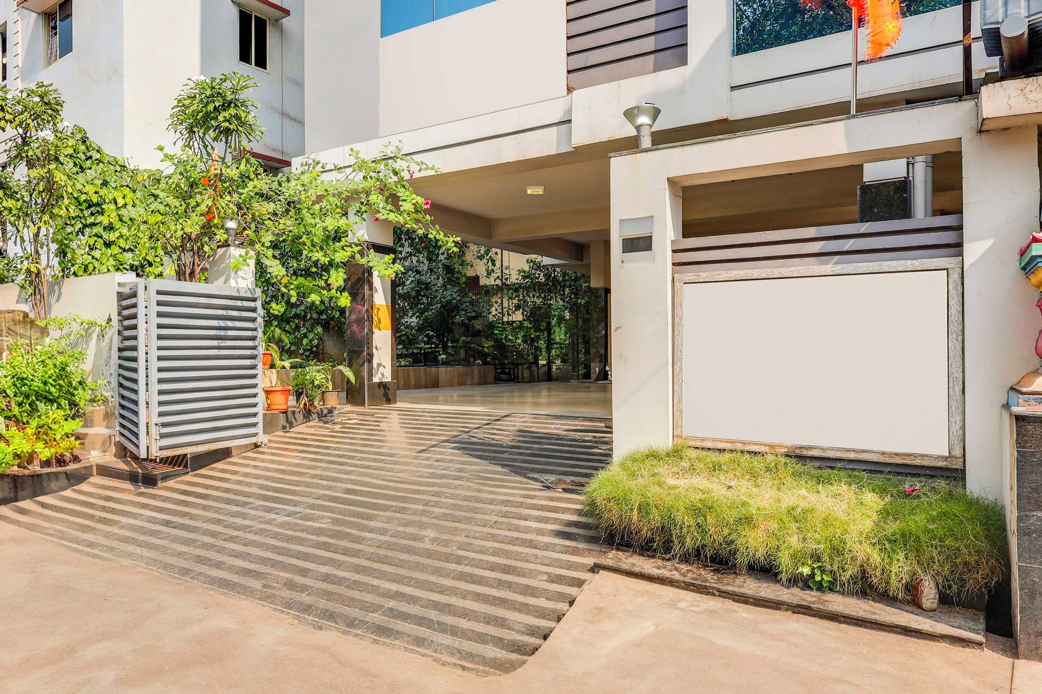 Un edificio moderno con una galería techada, plantas en macetas y un portón de garaje.