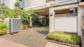 Un edificio moderno con una galería techada, plantas en macetas y un portón de garaje.