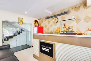 A reception desk with a sign indicating it's company-serviced, a clock, and a decorative horse statue. - Townhouse Oak Dwarka Nagar Ramatalkies (Visakhapatnam)