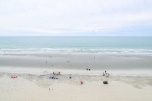A beach with people, a boat, and a lifeguard tower. - 3 BR Oceanfront Condo with Two Shared Pools and a Hot Tub! Atalaya Towers #703 (Garden City)