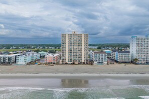Ein Hotelkomplex direkt am Strand mit mehreren Gebäuden, darunter ein hohes, zentrales Gebäude und einige kleinere.