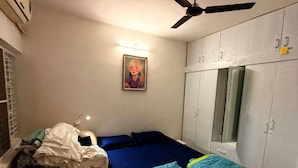 Un dormitorio con cama, ventilador de techo, armario y un cuadro en la pared.