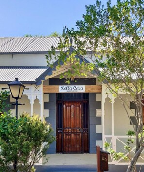 A guesthouse with a wooden entrance, a sign above the door, and a lamp post to the left.