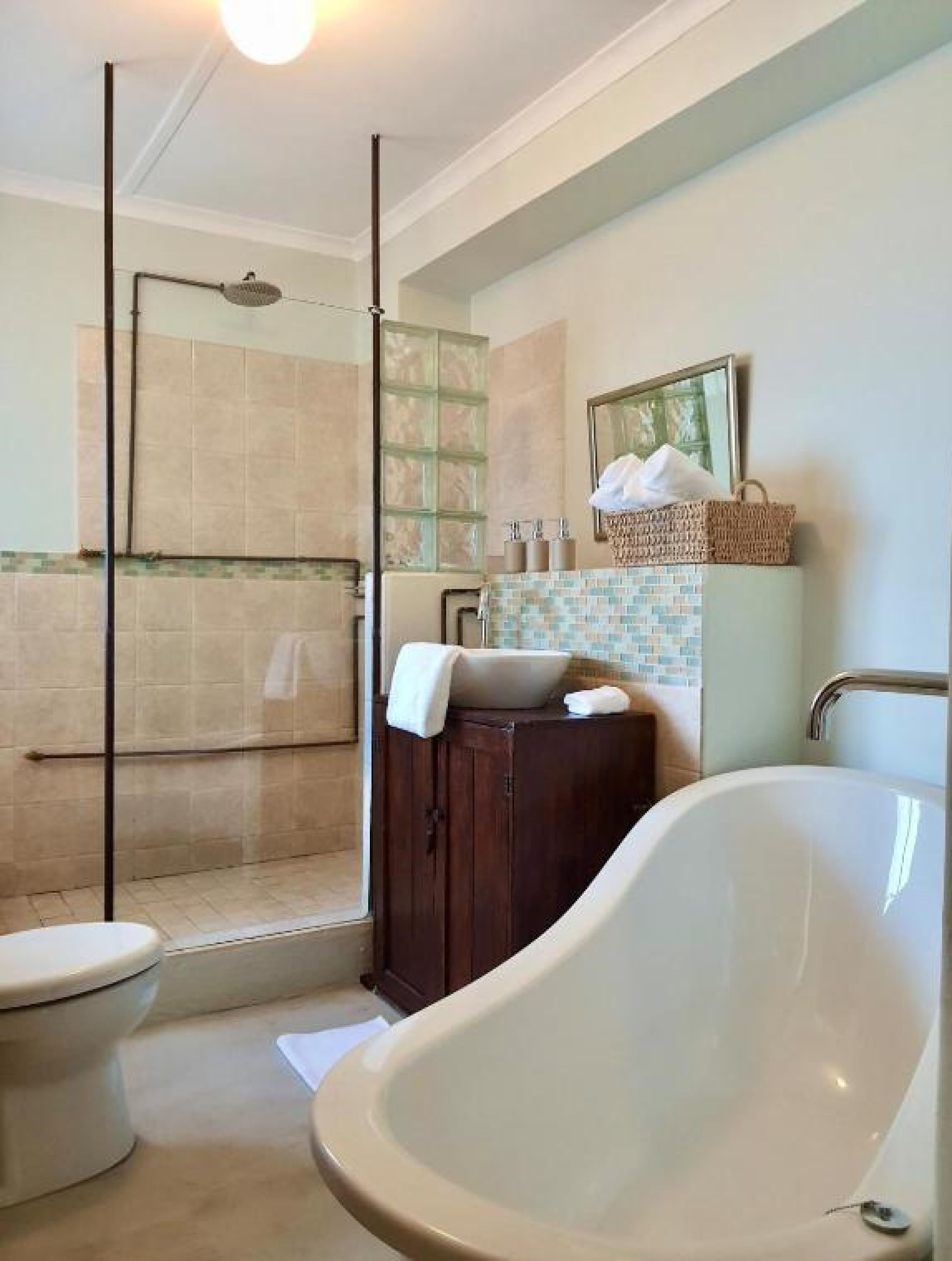 A bathroom with a bathtub, toilet, and glass shower enclosure.