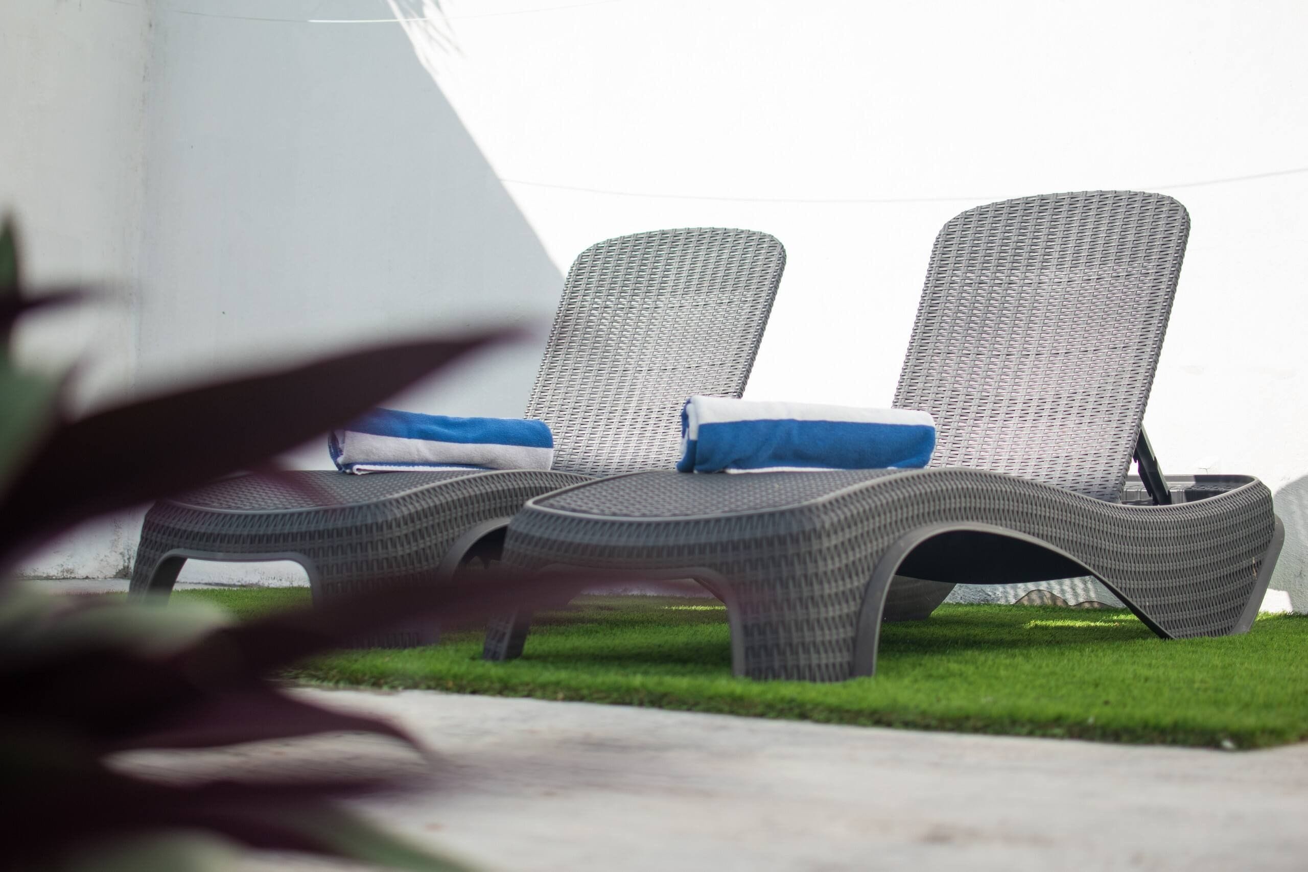 Two lounge chairs with blue cushions on a grassy area.