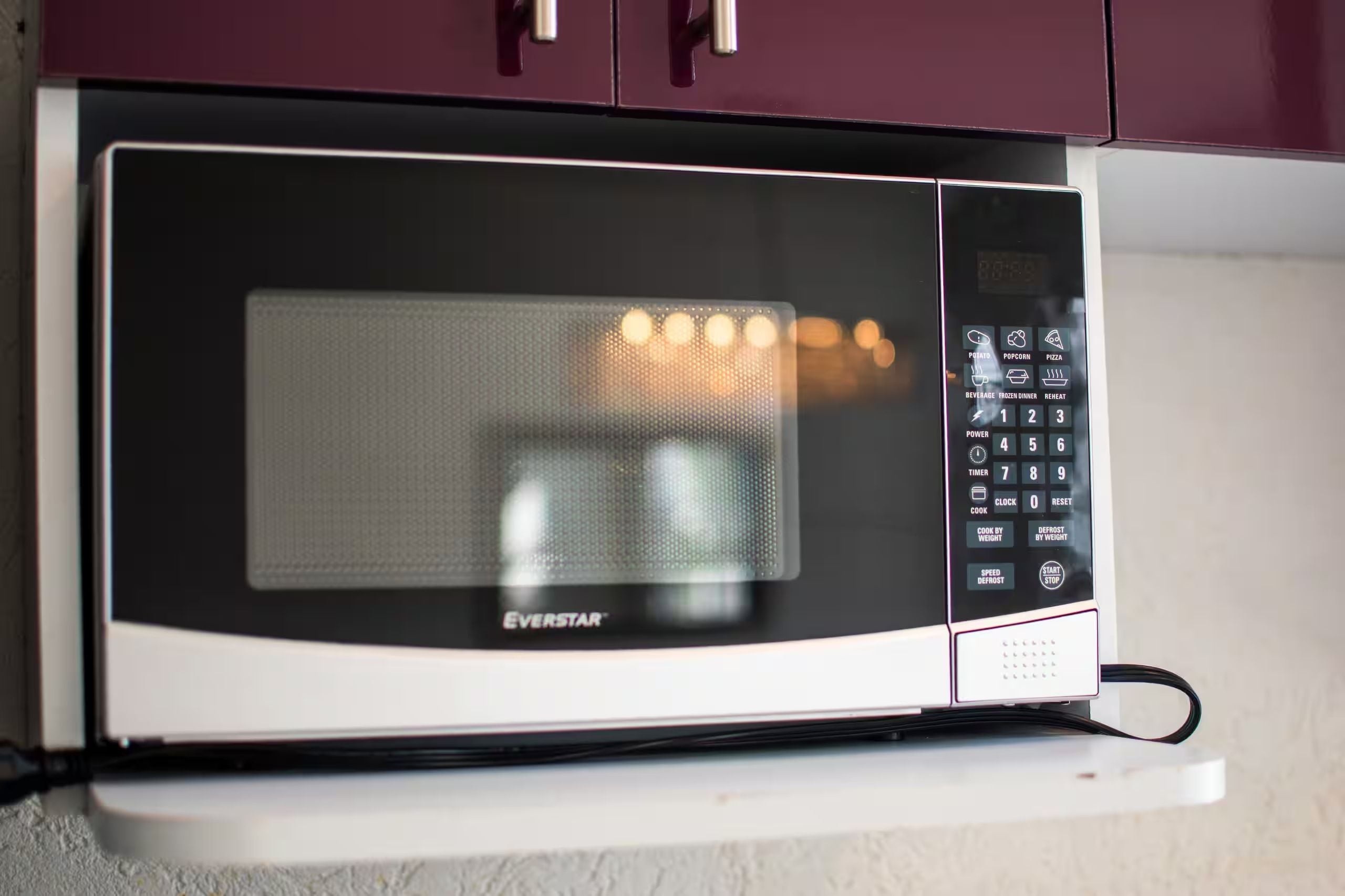 A microwave oven with a digital control panel, brand name 'EVERSTAR,' and a power cord plugged in.