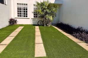 A well-maintained lawn with a concrete pathway leading to a white building with a window. - Casa Inn Retreat - Villas Morelos II (Puerto Morelos)