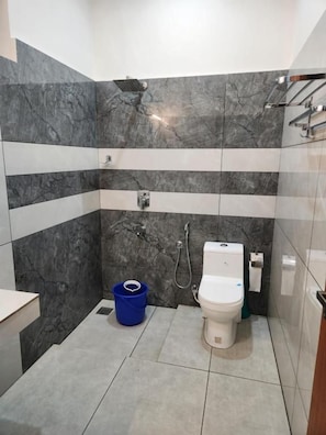 Ein Badezimmer mit Toilette, Dusche und einem blauen Eimer.