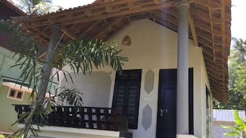 A single-story building with a tiled roof, a balcony with a railing, and a door.