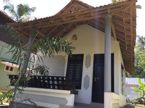 A single-story building with a tiled roof, a balcony with a railing, and a door.