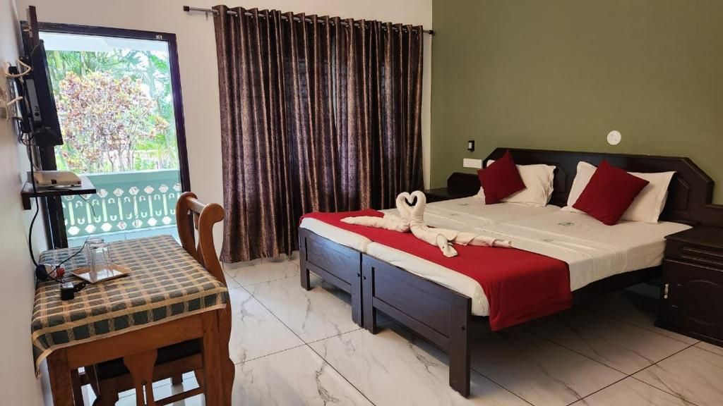 A hotel room with a bed, a desk, and a view of greenery outside.