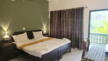 Een hotelkamer met een bed, nachtkastjes, een stoel en een balkon met gordijnen.
